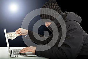 Computer hacker stealing money in the darkness