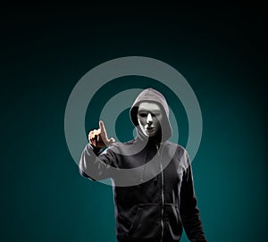 Computer hacker in white mask and hoodie. Obscured dark face. Data thief, internet fraud, darknet and cyber security