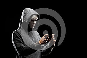 Computer hacker in white mask and hoodie. Obscured dark face. Data thief, internet fraud, darknet and cyber security