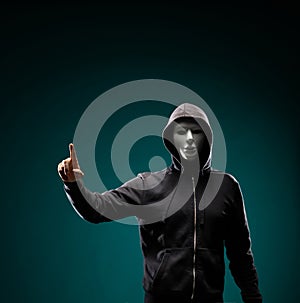 Computer hacker in white mask and hoodie. Obscured dark face. Data thief, internet fraud, darknet and cyber security