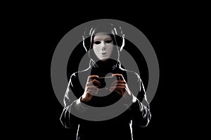 Computer hacker in white mask and hoodie. Obscured dark face. Data thief, internet fraud, darknet and cyber security