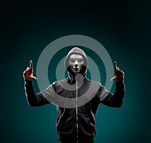 Computer hacker in white mask and hoodie. Obscured dark face. Data thief, internet fraud, darknet and cyber security