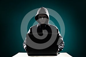 Computer hacker in white mask and hoodie. Obscured dark face. Data thief, internet fraud, darknet and cyber security