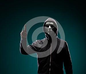 Computer hacker in white mask and hoodie. Obscured dark face. Data thief, internet fraud, darknet and cyber security