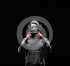 Computer hacker in white mask and hoodie. Obscured dark face. Data thief, internet fraud, darknet and cyber security