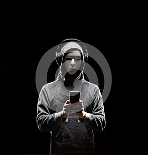 Computer hacker in white mask and hoodie. Obscured dark face. Data thief, internet fraud, darknet and cyber security