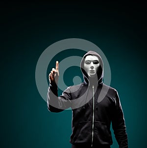 Computer hacker in white mask and hoodie. Obscured dark face. Data thief, internet fraud, darknet and cyber security