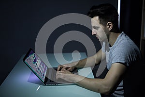 Computer hacker working in dark room programing at night
