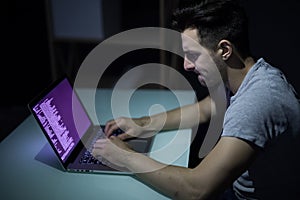 Computer hacker working in dark room programing at night