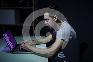 Computer hacker working in dark room programing at night