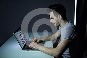 Computer hacker working in dark room programing at night