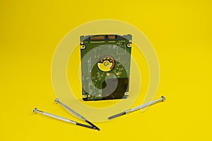 Computer hard disk drive isolated on yellow with a screwdrivers