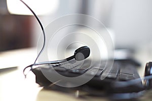 Computer with headphone and mini microphone near keyboard on wooden desk in workspace area in Call Center and telemarketing