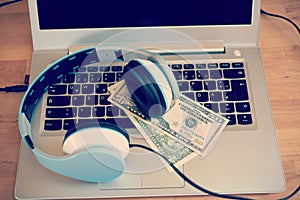 Computer with headphones and dollar bank notes