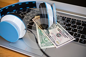 Computer with headphones and dollar bank notes