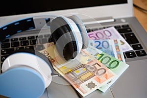 Computer with headphones and euro bank notes