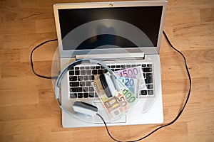 Computer with headphones and euro bank notes