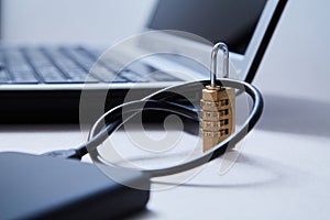 Computer or internet security. Data protection concept: external hard drive, lock and laptop on the background