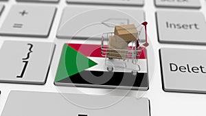 Computer keyboard key with flag of Sudan and shopping cart with cartons, online shopping conceptual 3d rendering