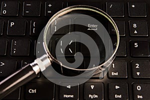 Computer keyboard and magnifying glass, close-up. Computer security concept