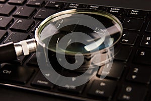 Computer keyboard and magnifying glass, close-up. Computer security concept