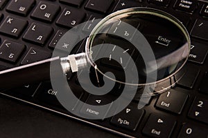 Computer keyboard and magnifying glass, close-up. Computer security concept