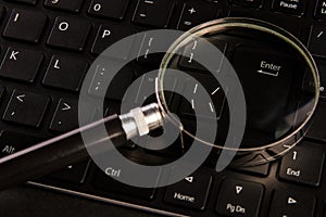 Computer keyboard and magnifying glass, close-up. Computer security concept