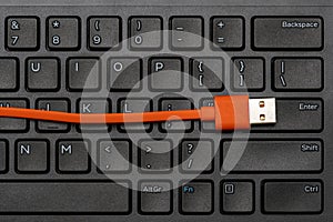 Computer keyboard and orange USB cable