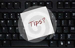 Computer keyboard with a pink sticky note with text tips