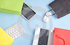 Computer keyboard, tablet, mouse and shopping bags on the blue background