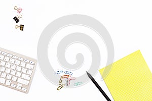 Computer keyboard, yellow Notepad paper clip and black pencil on a white background. Minimal business concept for office.