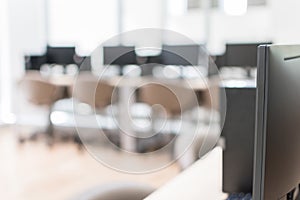 Computer lab blur background with pc desktop computer machine in blurry empty school class room or office desk interior workspace