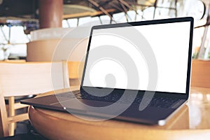 Computer laptop with blank white desktop screen on wooden table in cafe