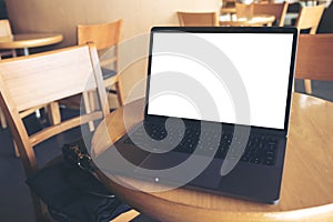 Computer laptop with blank white desktop screen on wooden table in cafe