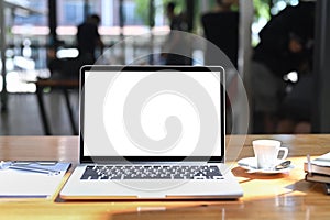 Computer laptop, coffee cup and document on wooden table in office.