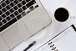 Computer laptop with cup of black coffee, pen and spiral opened