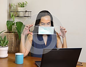 Computer laptop and houseplant ,showing how to wear hygienic mask.working at home and protection from covid-19 concept