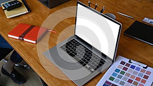 Computer laptop and paperwork on wooden table at creative workplace.