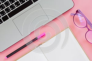 Computer laptop with a pen, an opened notebook and eyeglasses on