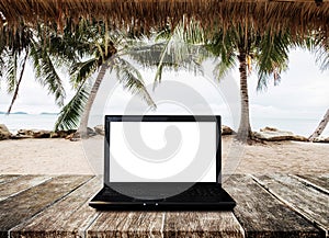 Computer laptop on wooden table, at the beach in Summer. Clipping path computer screen