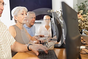 Computer lessons for elderly people in nursing home. Group of seniors learning to use computers in class