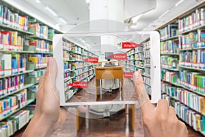 computer in a libAugmented reality education concept. Hand holding digital tablet smart phone use AR application to check library