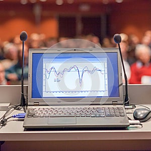 Computer and microphone on rostrum at business event.