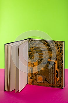 Computer motherboard in a large open book on a colored background