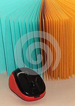 Computer mouse on the background of colored sheets of green and yellow paper