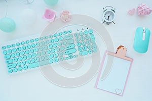 Computer mouse and keyboard in mint white, pink clipboard, paper clip, candle, alarm clock, pink paper flower on a white table. Fl