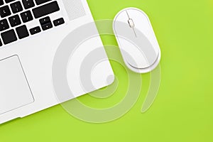 Computer mouse and laptop on a green background isolated, flat lay.
