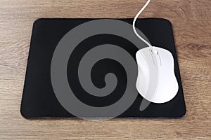 Computer mouse with mousepad on wooden table