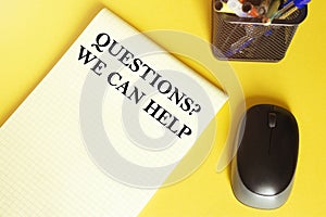 Computer mouse, pens, felt-tip pens, notepad with text Questions We Can Help on a yellow background