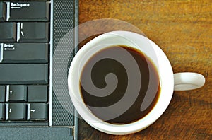 Computer notebook and black coffee cup on table